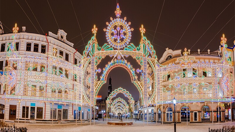 Colorful lights on buildings located on snow covered street.