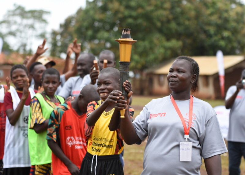 Coach and smiling young athlete proudly hold the torch.