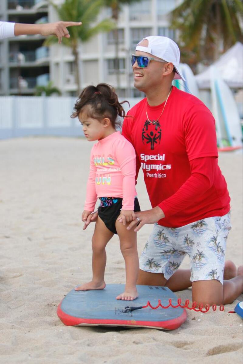 Young girl standing on a buggy board with an adult assisting her.