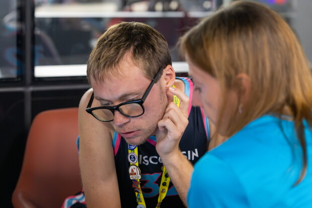 Athlete and Special Olympics representative looking down and looking over something off camera. 