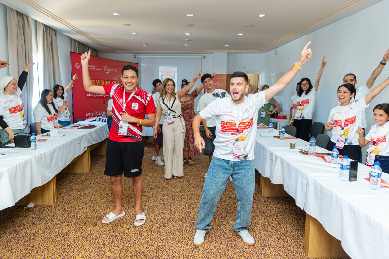 a group of people behind tables, and a group of people in the center of the room dancing