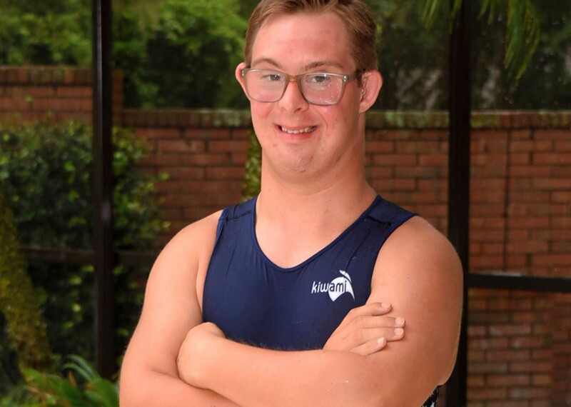 Chris Nikic standing in front of a pool in Special Olympics Training gear