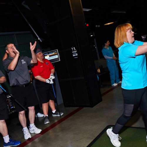 Woman hitting a ball with a golf club. 
