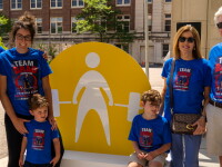 Family members wearing matching "Team Brad" shirts pose in front of a Special Olympics USA Games display on the University of Minnesota campus. They are supporting Tennessee powerlifting athlete Brad Davis and cheering on Special Olympics athletes competing at the 2026 USA Games.