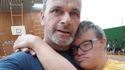 Athlete Kai Bodenstein hugging Coach Rob van Someren Brand in a gymnasium. 