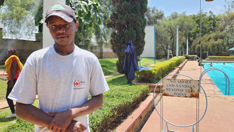 Athlete Francis Mutugu Munyaka smiles at the camera while standing in front of a swimming pool.