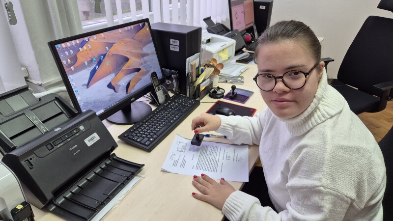 Athlete sitting at a desk stamping a document. 