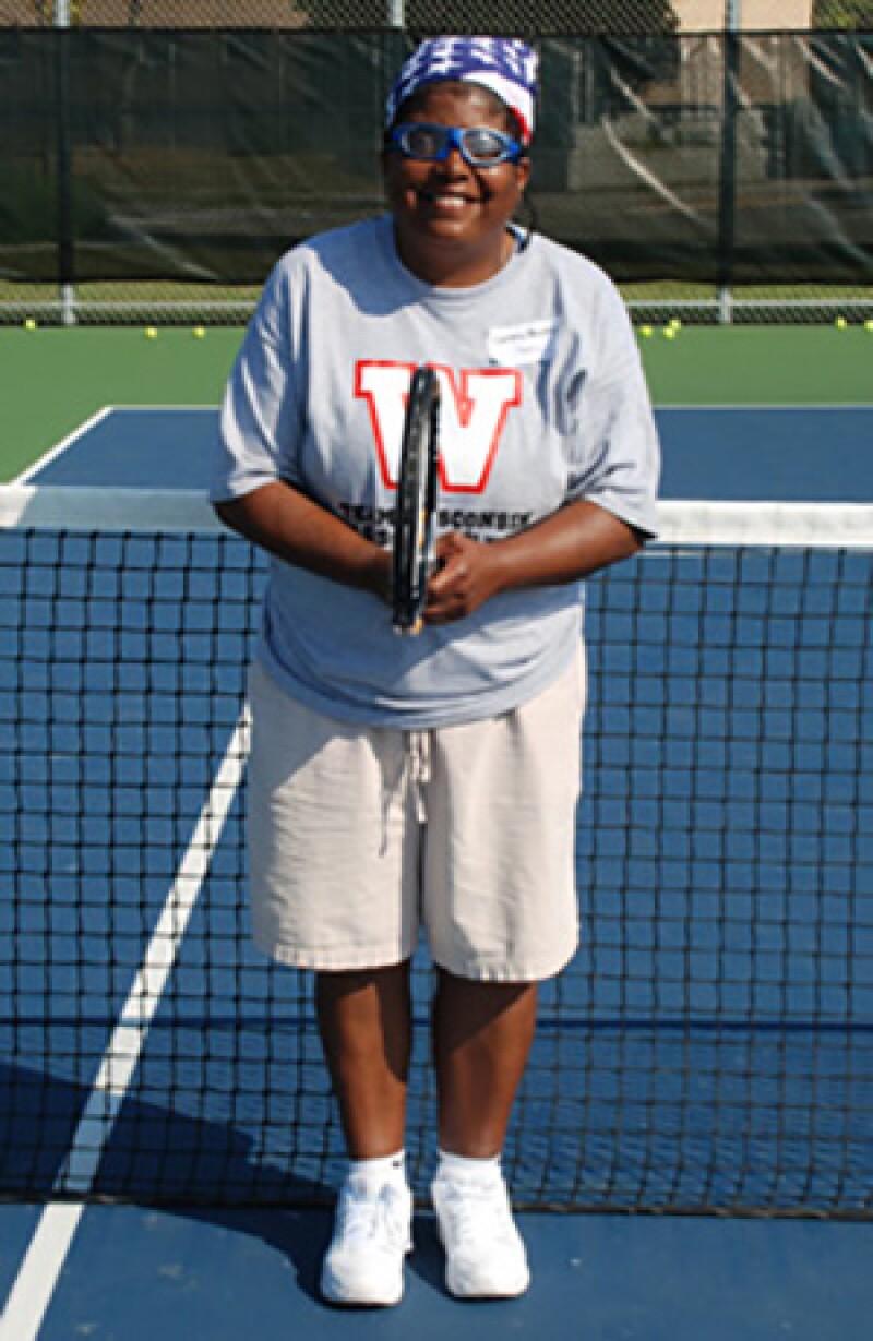 Cindy Bentley on the tennis court holding a racket in front of the net.
