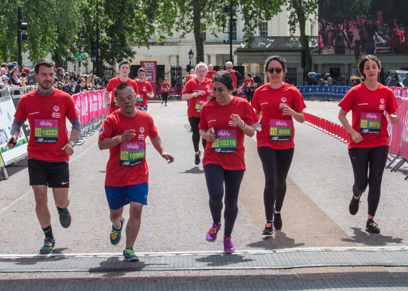 Runners in red t-shirts running towards the camera across a finish line. 