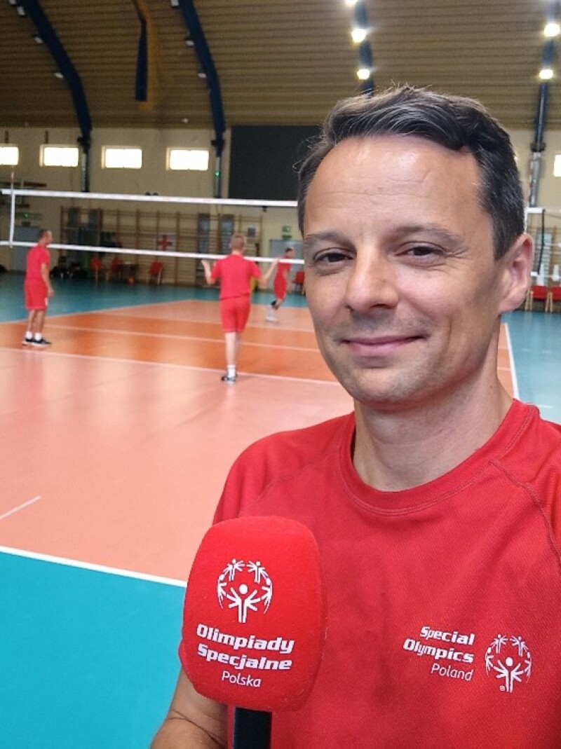 man standing on a volleyball court being interviewed.