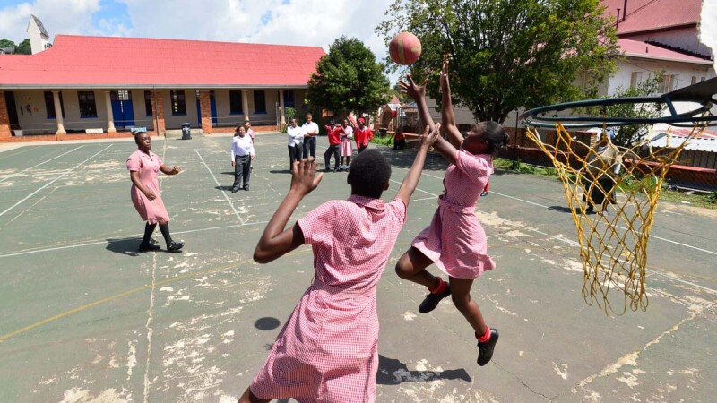 Female athletes practice netball on the court.