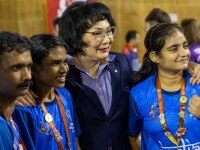 Three athletes in blue India jerseys smile and pose with BWF President Khunying Patama Leeswadtrakul.