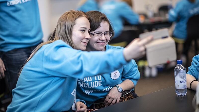 Two girls sitting side by side taking a selfie.