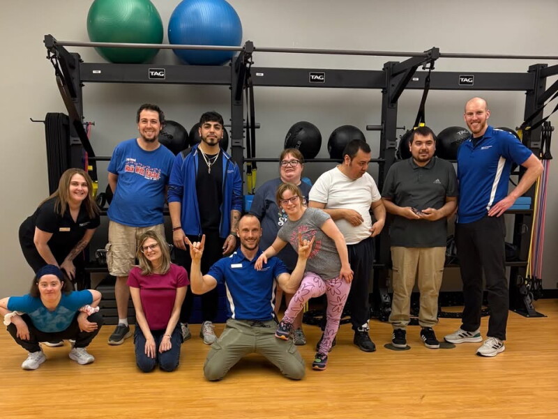 Un grupo de personas se para frente a un equipo de fitness y sonríe para una foto.