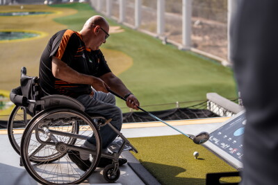 Man in wheelchair playing topgolf. 