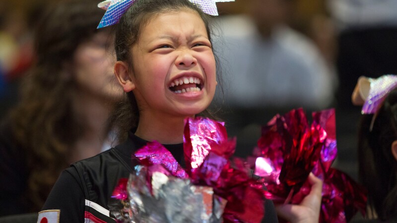 Cheerleader for Japan cheering and ruffling her pompoms. 