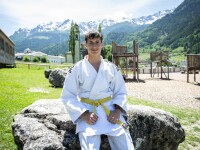 Judoka Alex Leimsider wears a judogi while he poses for a photo with mountains in the background