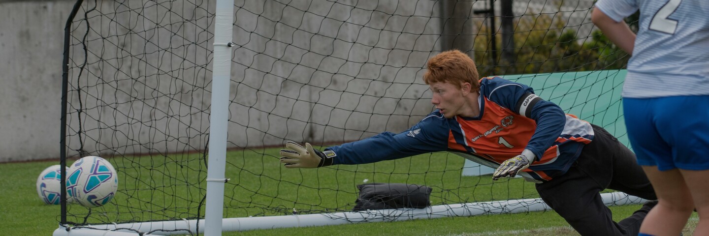 keeper diving for the ball before it makes it into the net. 