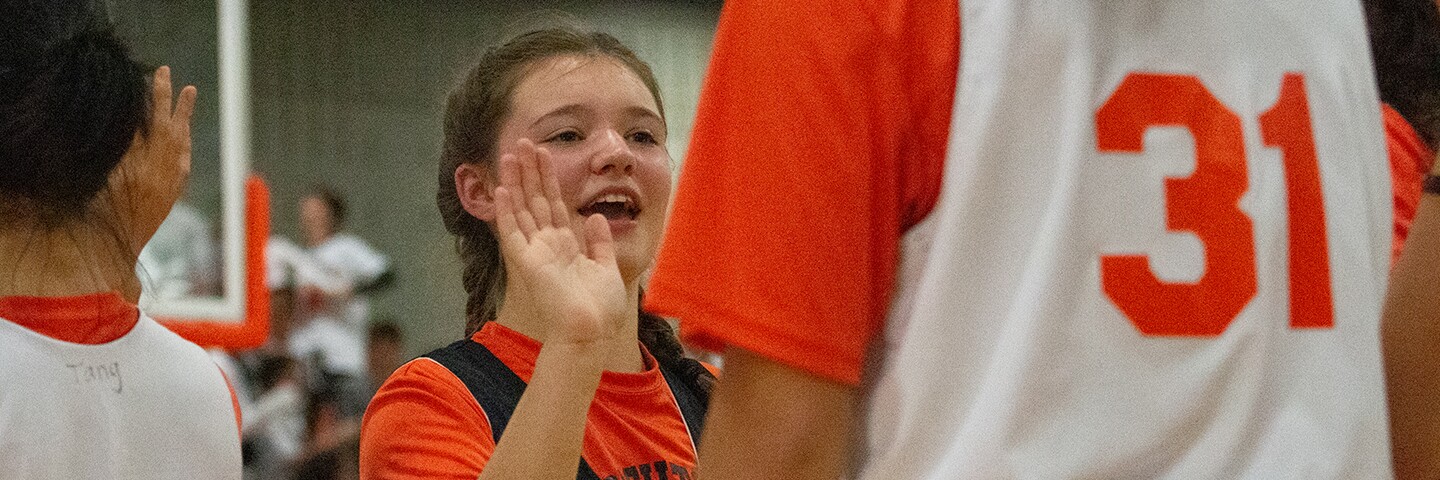 Young girl giving another person a high-5.