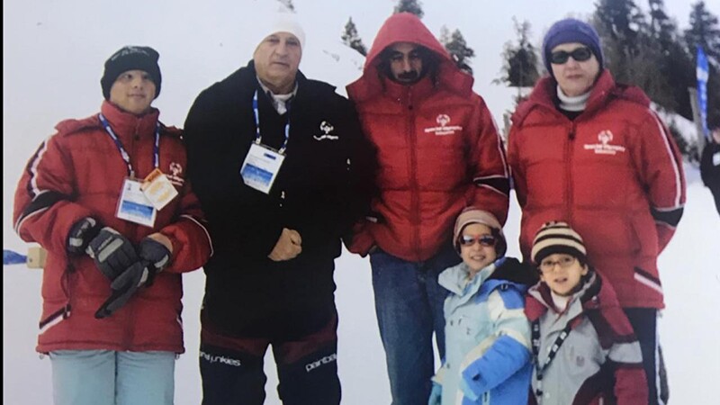Three male adults, one female adult, and two young children pose for a group photo. 