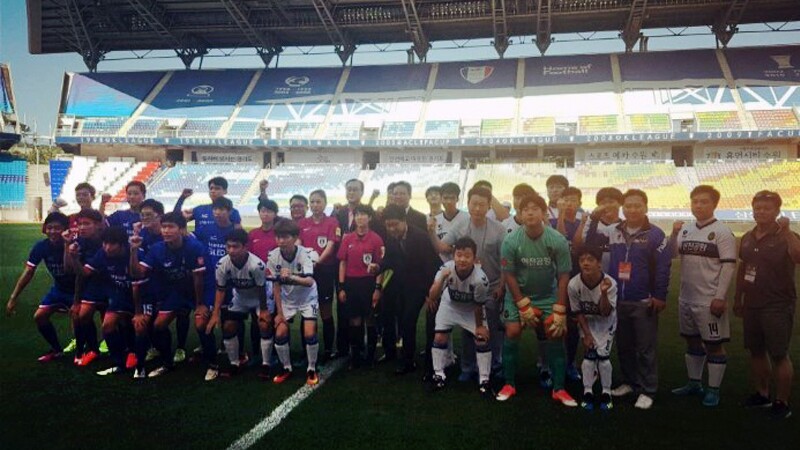 The Unified football match in collaboration with Incheon United FC and Suwon Samsung Bluewings took place on July 18th in Korea. A group of unified players stand in a row on the field with the bleacher behind them.