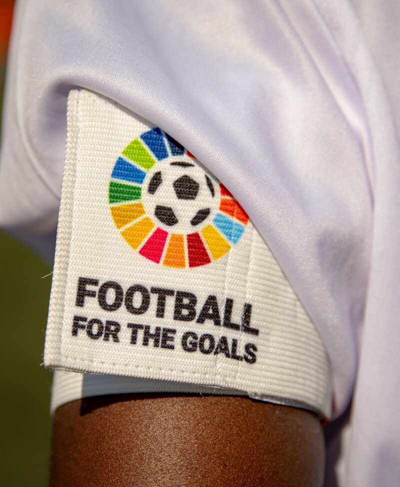 A white armband with a soccer ball on it. The text "Football for the Goals" appears under the soccer ball. 