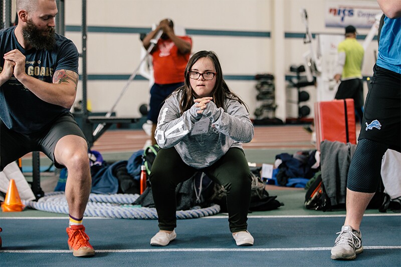 Athletes performing squats in a gym setting.
