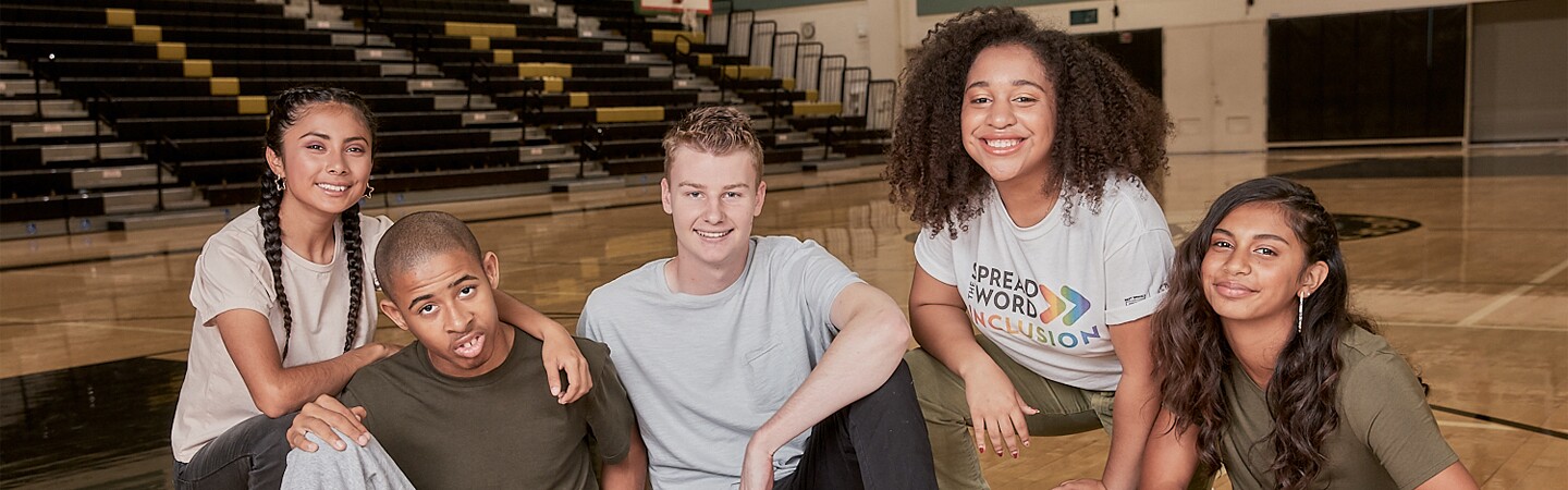 Five young adults in gymnasium together in a group.