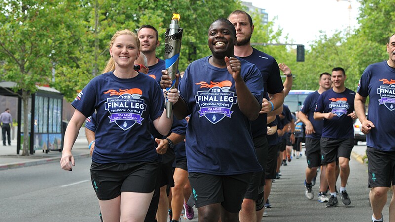 Group of athletes on the street running with the Flame of Hope.