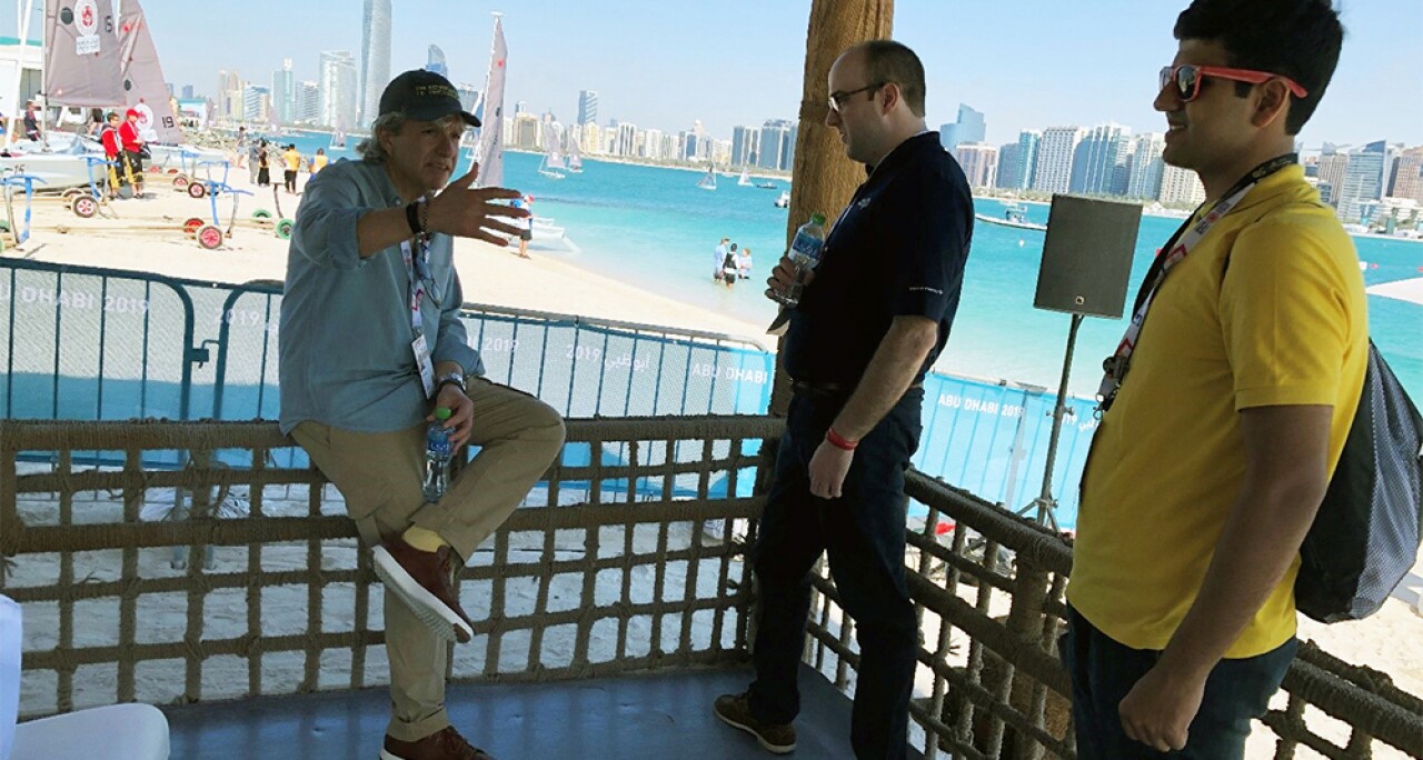 Two young adults listen as an adult standing outside by the beach.