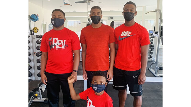 Eric and his family members pose together inside a gym.