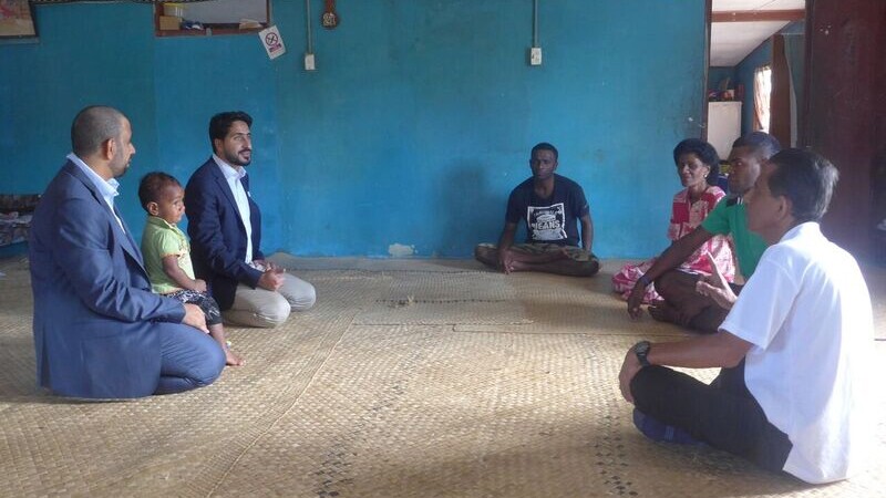 Abu Dhabi representatives and a Kenya athletes family speak together in a house.