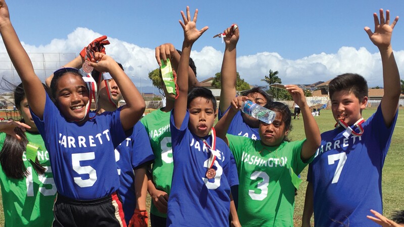 Jarrett Middle vs Washington Middle students in Hawaii together in a small group in a field.