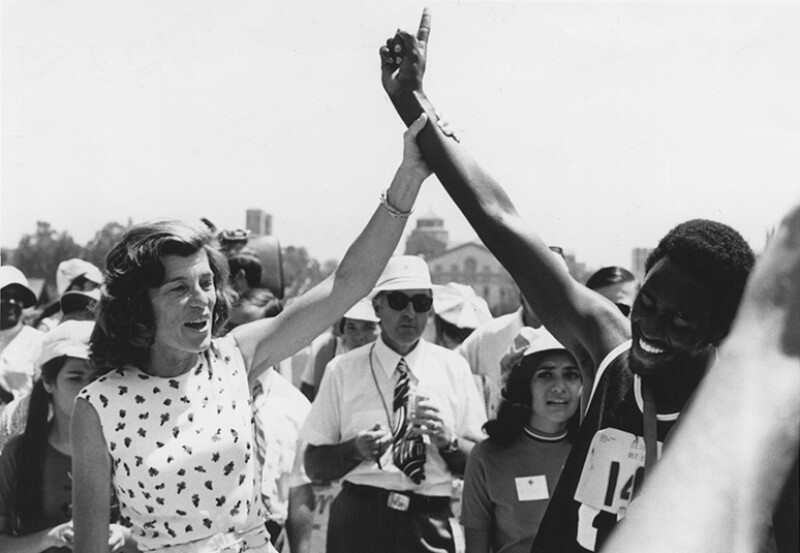 Eunice Kennedy Shriver holding an athletes arm up in victory.