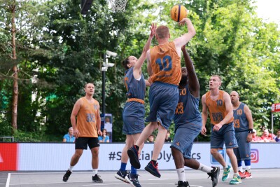 A group of basketball players in grey and orange vie for the ball on a basketball court. 