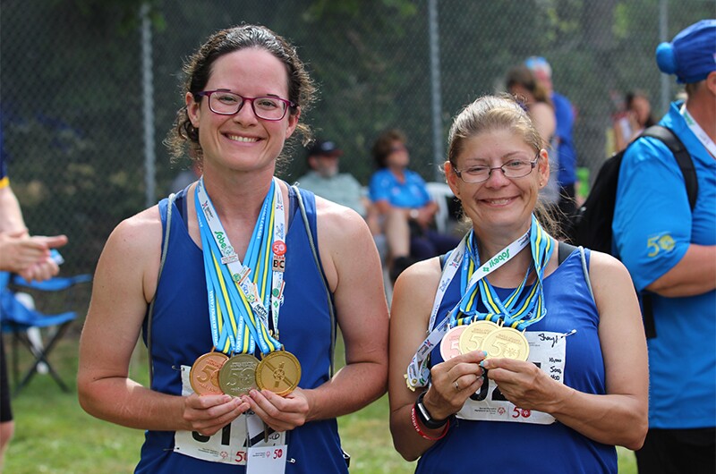 Ashley Adie standing next to another athlete and both are showing off their medals.
