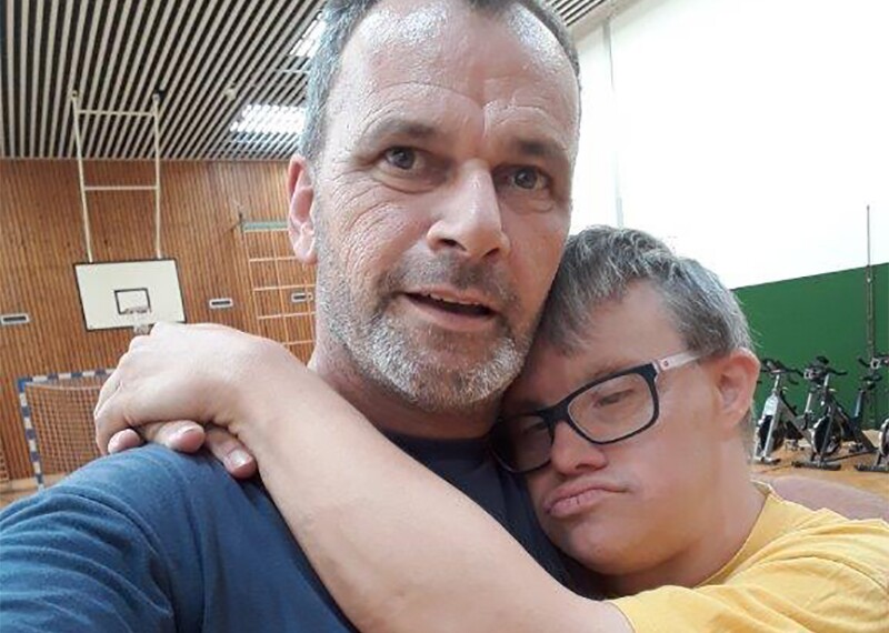 Athlete Kai Bodenstein hugging Coach Rob van Someren Brand in a gymnasium.