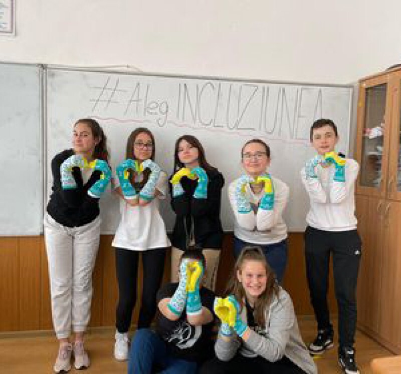 A group of seven students with socks on their hands making hearts. 
