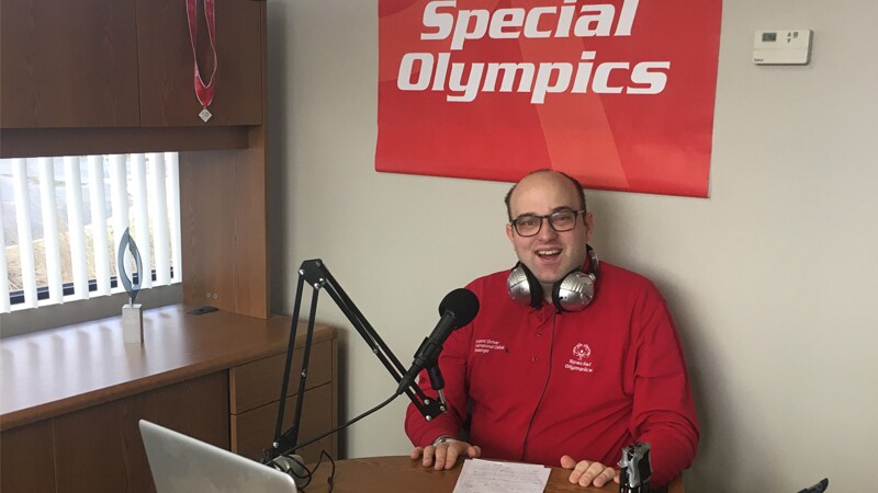 Daniel Smrokowski sitting at a round table with his podcast equipment in front of him.