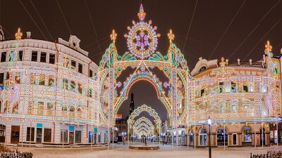 Colorful lights on buildings located on snow covered street.