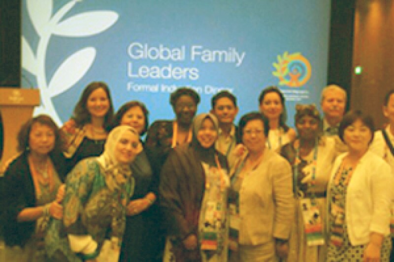 Athletes and family members in a small group in front of a projection that reads: Global Family Leaders