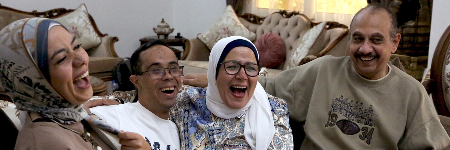 Family sitting on a couch laughing. 