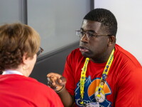 Man speaking and gesturing while a woman listens. 