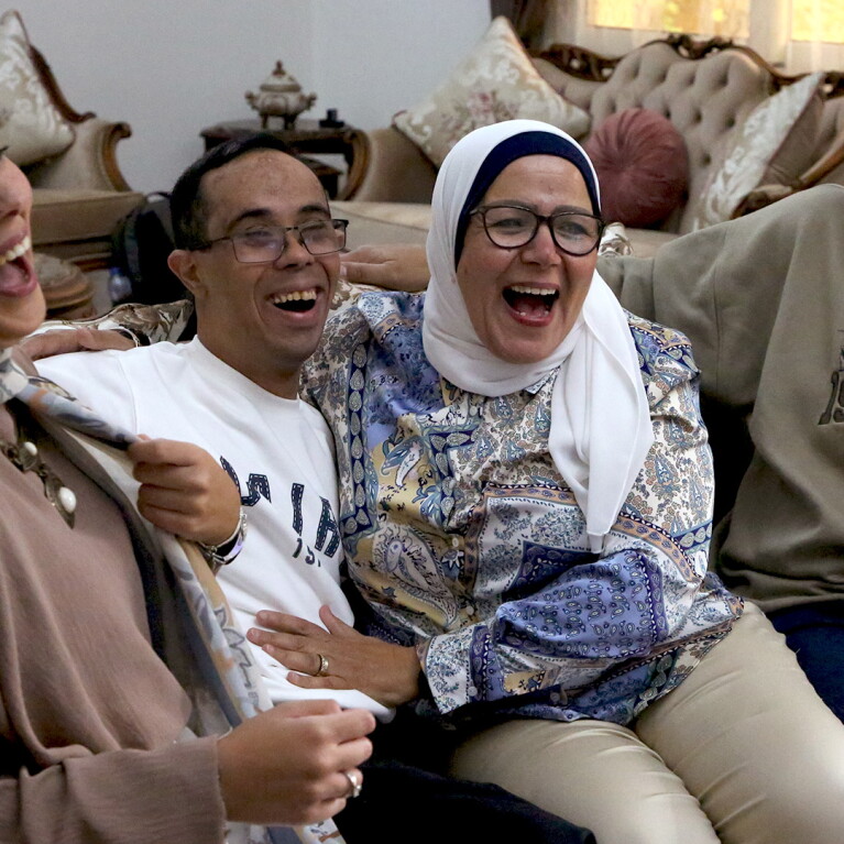 Family sitting on a couch laughing. 