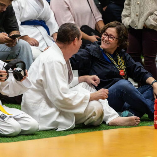 A woman and man look at each other at the sidelines of a judo match. 