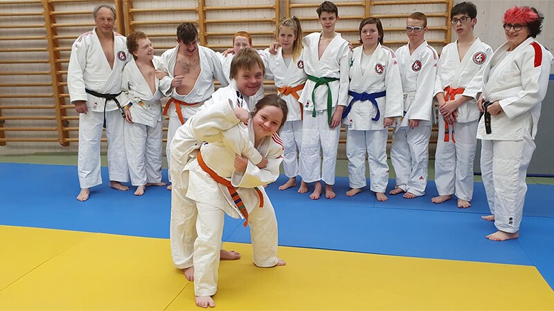 Two athletes demonstrating a move while the class observes.