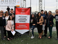 School representatives and unified teams standing by a national unified champion school banner. 