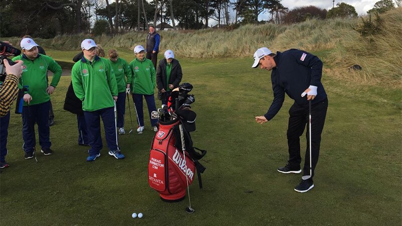 Padraig Harrington playing golf while athletes watch.