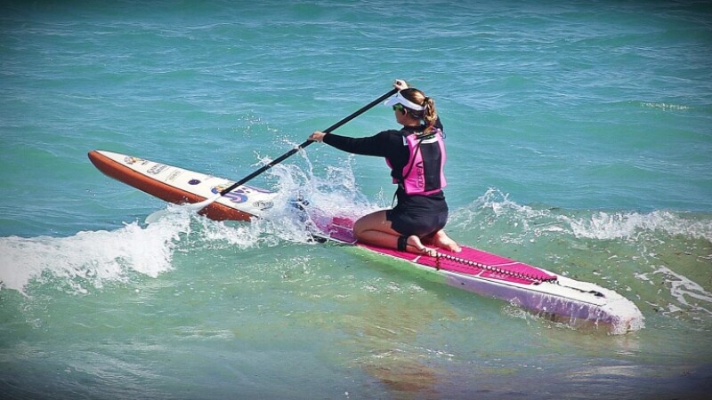 Special Olympics athlete rides stand up paddleboard on her knees. 