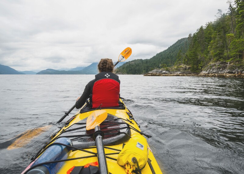 Female kayaker paddling into the openness of the lake.